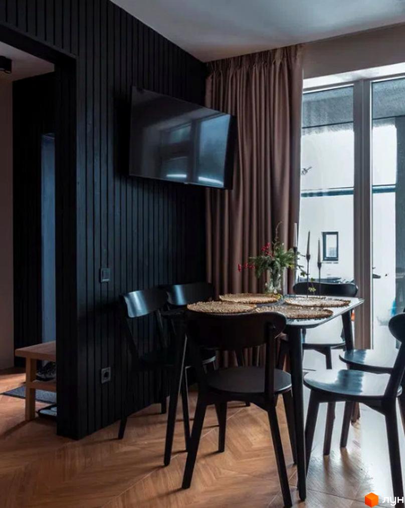 Інтер'єр їдальні в житловому комплексі КМ Solomon Residence з темними дерев'яними стінами, телевізором та обіднім столом.