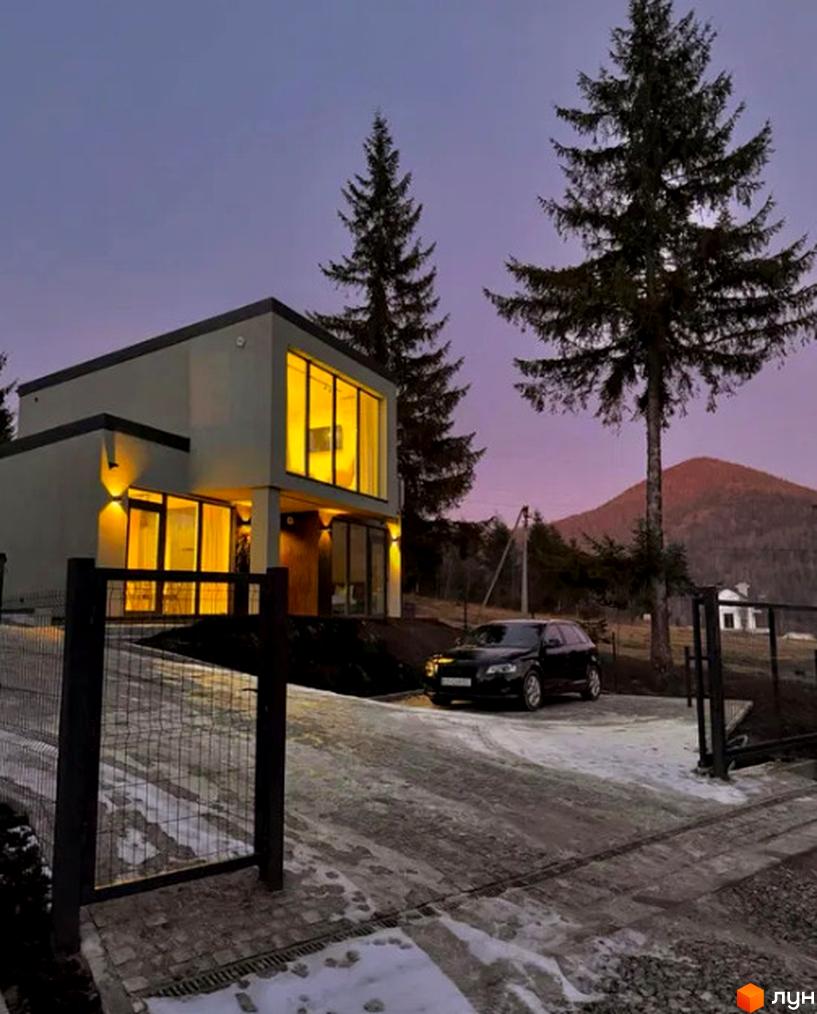 Котеджне містечко КМ Solomon Residence: двоповерховий будинок з великими вікнами та підсвіткою, прибудинкова територія з дорогою та деревами.