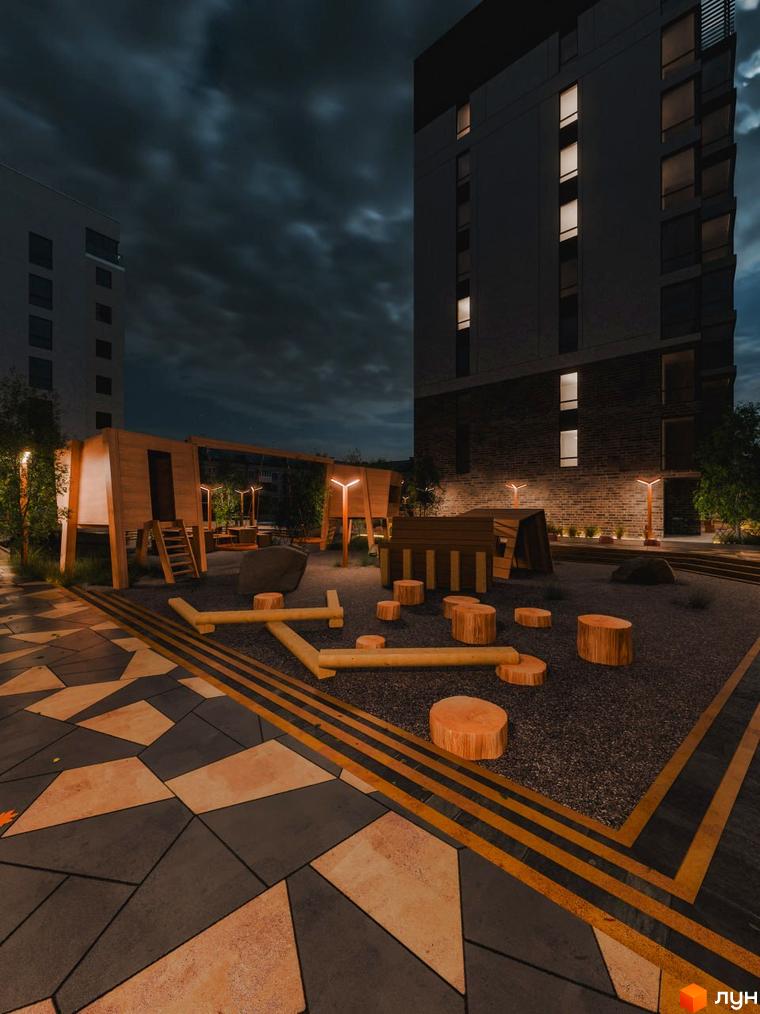 Житловий комплекс Перемога: фасади будинків та облаштований дитячий майданчик з дерев'яними елементами та освітленням у вечірній час.