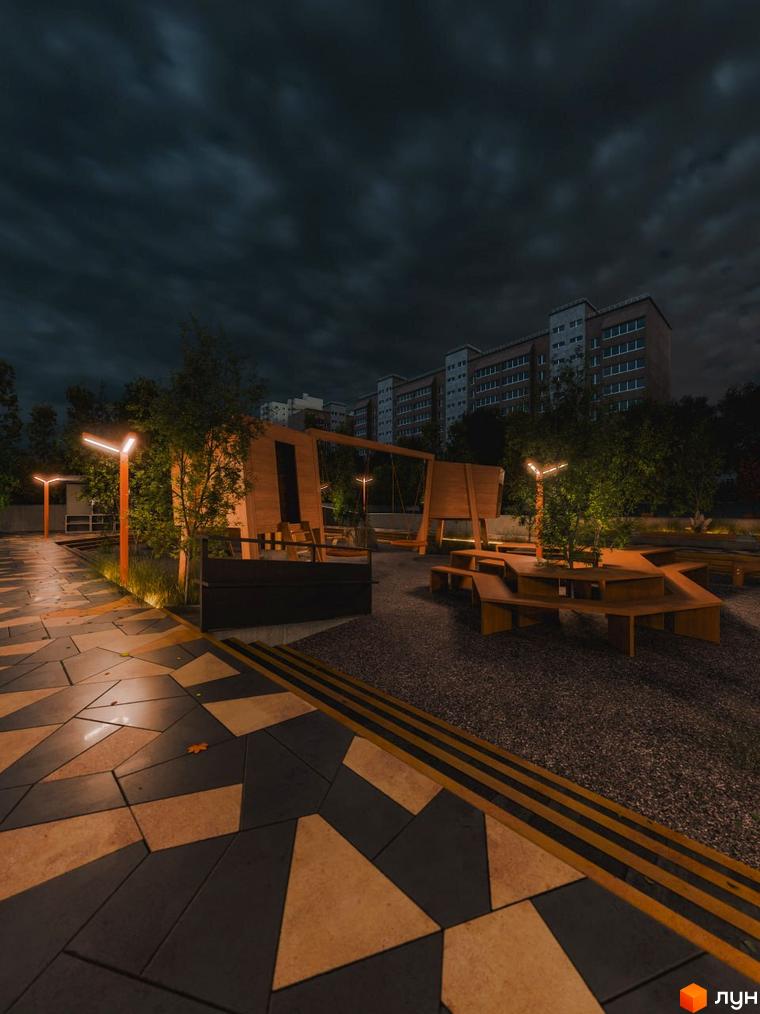 Зовнішній вигляд ЖК Перемога вночі з освітленою прибудинковою територією та лавками.