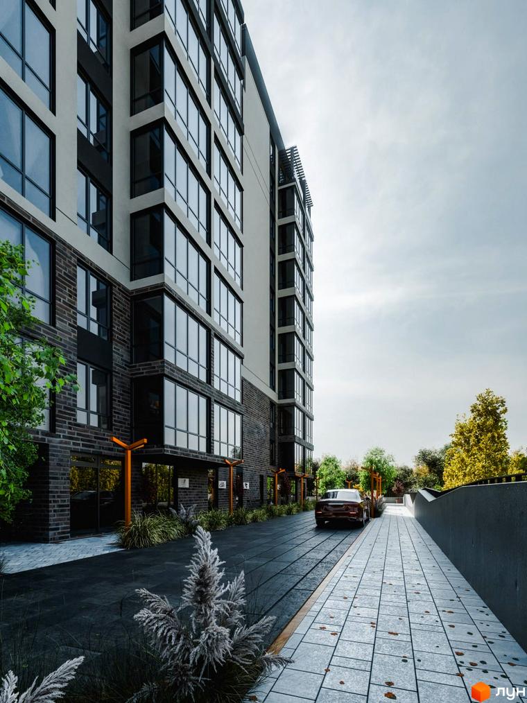 Зовнішній вигляд житлового комплексу Перемога з цегляним фасадом та великими вікнами. Прибудинкова територія з доріжкою та деревами.