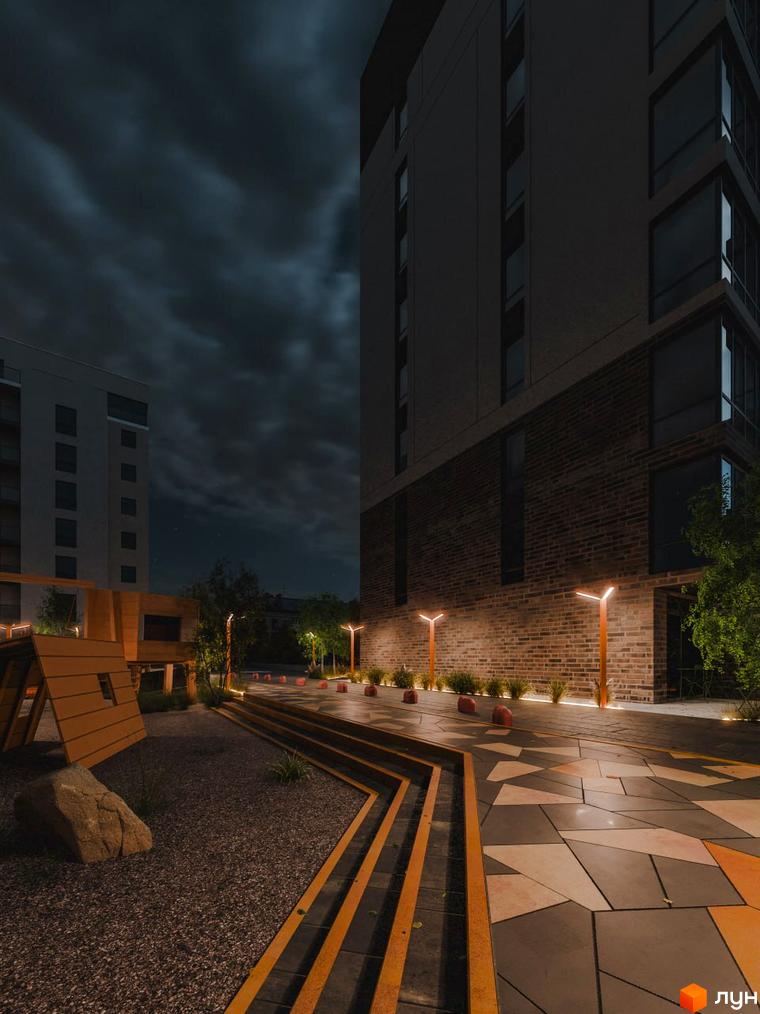 Житловий комплекс Перемога: фасади будівель та освітлена прибудинкова територія з дитячим майданчиком та мощенням у вечірній час.