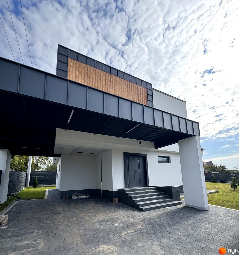 Котеджне містечко Lake House Sokilnyky: фасад будинку з дерев'яними вставками та навісом, вимощена бруківкою прибудинкова територія.