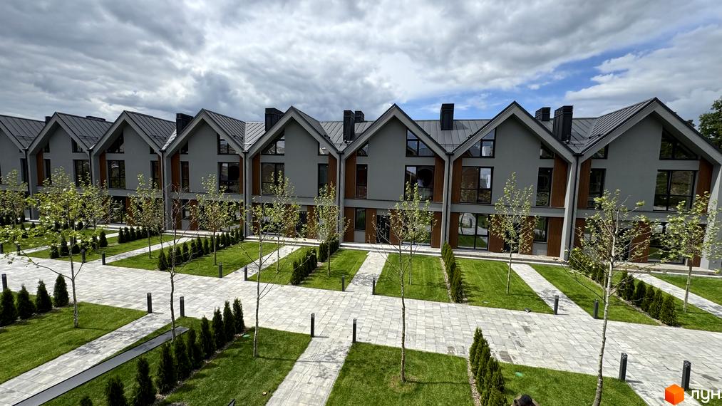 Зовнішній вигляд таунхаусів Legend Town з сірими фасадами та темними дахами, доглянута прибудинкова територія з газонами та доріжками.