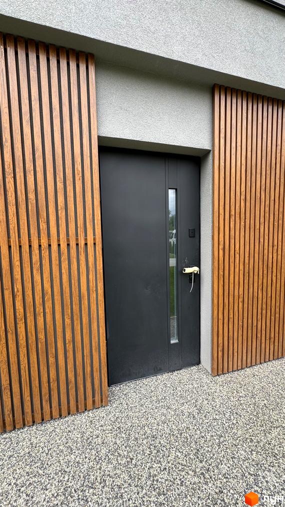 Вхідна група таунхаусу Legend Town з дерев'яними панелями та сірим фасадом. Навколо будинку гравійна доріжка.