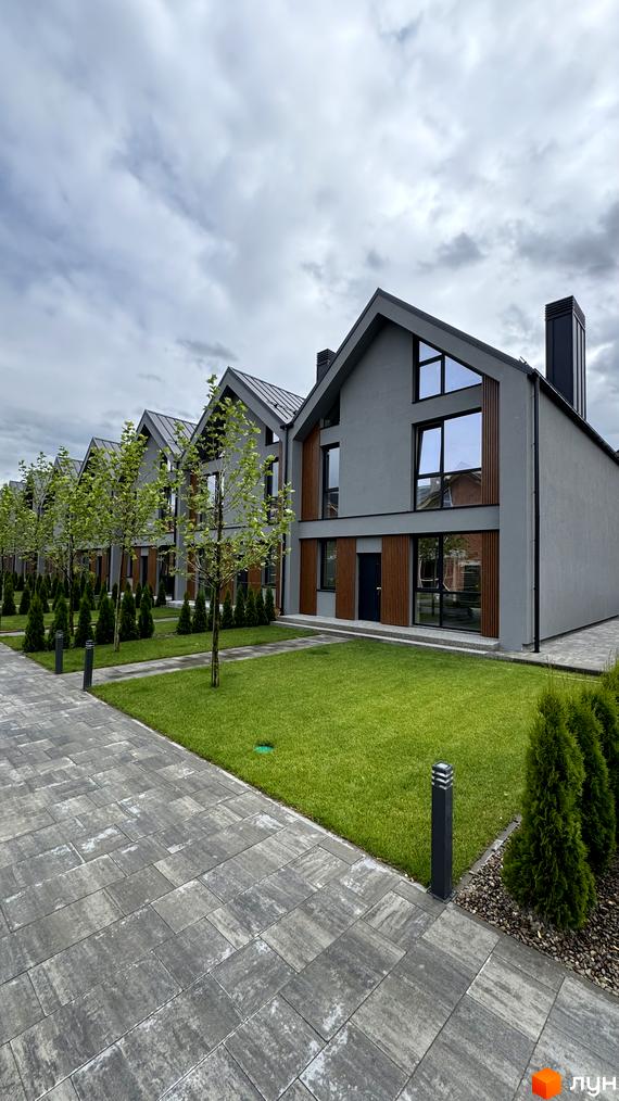 Таунхауси Legend Town з сірим фасадом, дерев'яними вставками та великими вікнами. Доглянута прибудинкова територія з газоном та бруківкою.