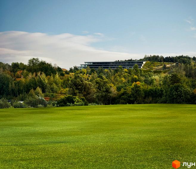 Житловий комплекс Lion Hills з багатоповерховими будівлями, розташований на пагорбі серед зелені. Перед ним - доглянутий зелений газон.