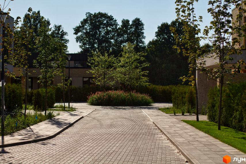 Котеджне містечко О.Краса: фасади будинків з цегли та бетону, доглянута прибудинкова територія з бруківкою та зеленими насадженнями.