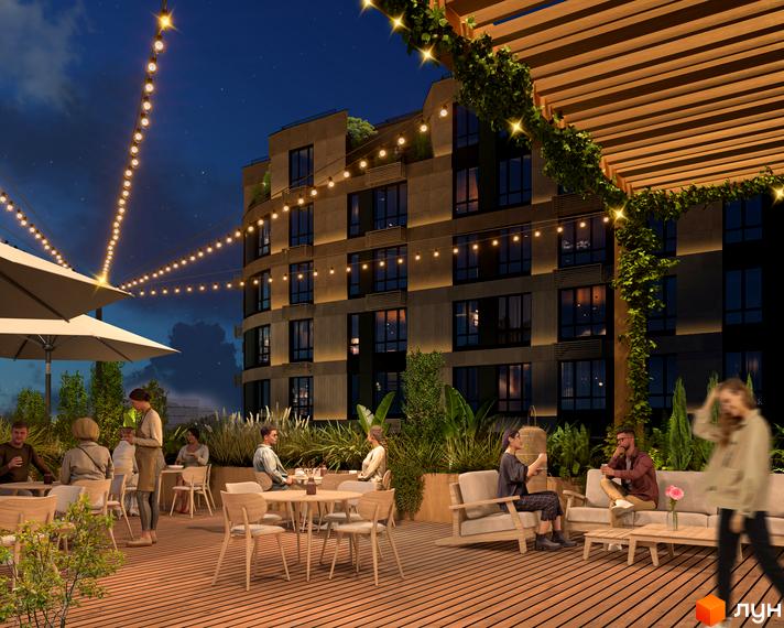 Житловий комплекс RIVERVILLE з терасою та освітленням у вечірній час. На терасі розташовані столики, стільці та дивани, оточені зеленню.
