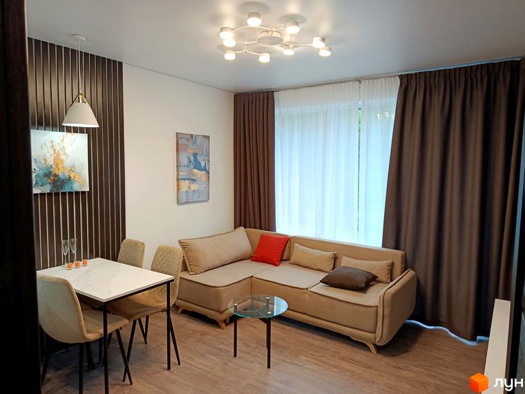 Інтер'єр квартири в житловому комплексі Вертикаль з диваном, обіднім столом та картинами на стінах.