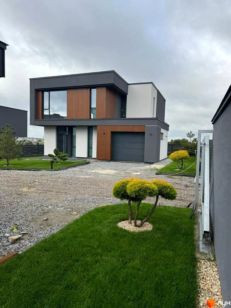 Зовнішній вигляд будинку в Котеджному містечку Prime Hill. На передньому плані зелений газон та декоративні кущі.