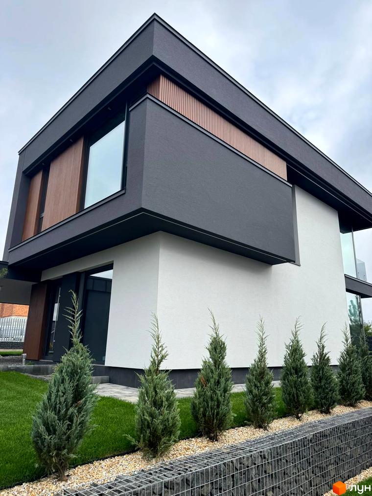 Зображення будинку в Котеджному містечку Prime Hill. Двоповерхова будівля з великими вікнами та озелененою територією.