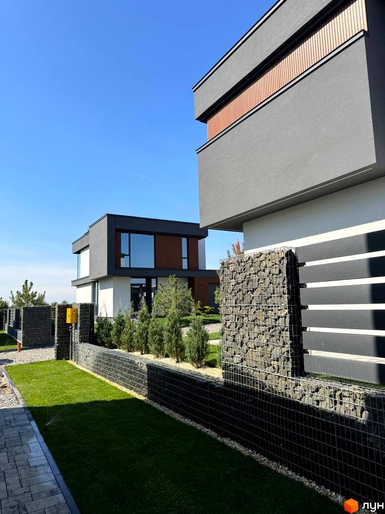 Зовнішній вигляд будинку в Котеджному містечку Prime Hill. На прибудинковій території зелений газон та декоративні насадження.