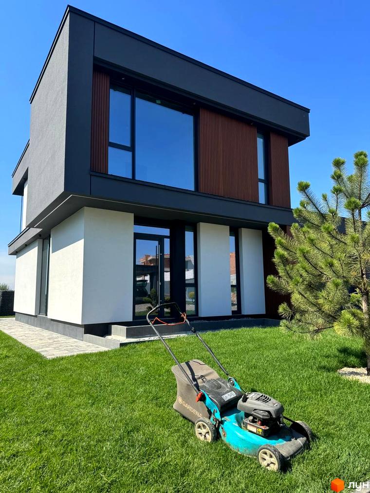 Зовнішній вигляд двоповерхового будинку в Котеджному містечку Prime Hill. Навколо будинку зелений газон та невелика ялинка.