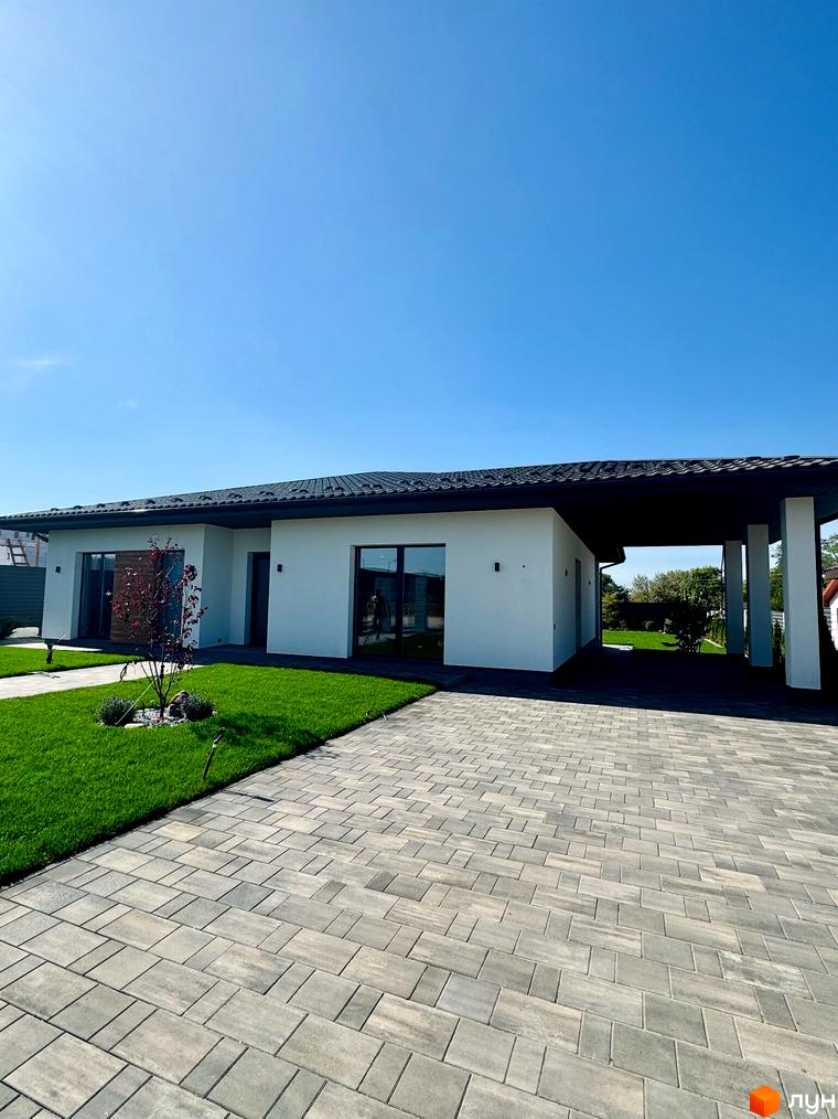 Зображення будинку в Котеджному містечку Bratske Home з великим подвір'ям та тротуарною плиткою. Вигляд фасаду та ландшафтного дизайну.