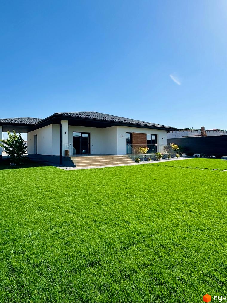 Зображення будинку в Котеджному містечку Bratske Home. На фото видно газон перед будинком та частково фасад будівлі.