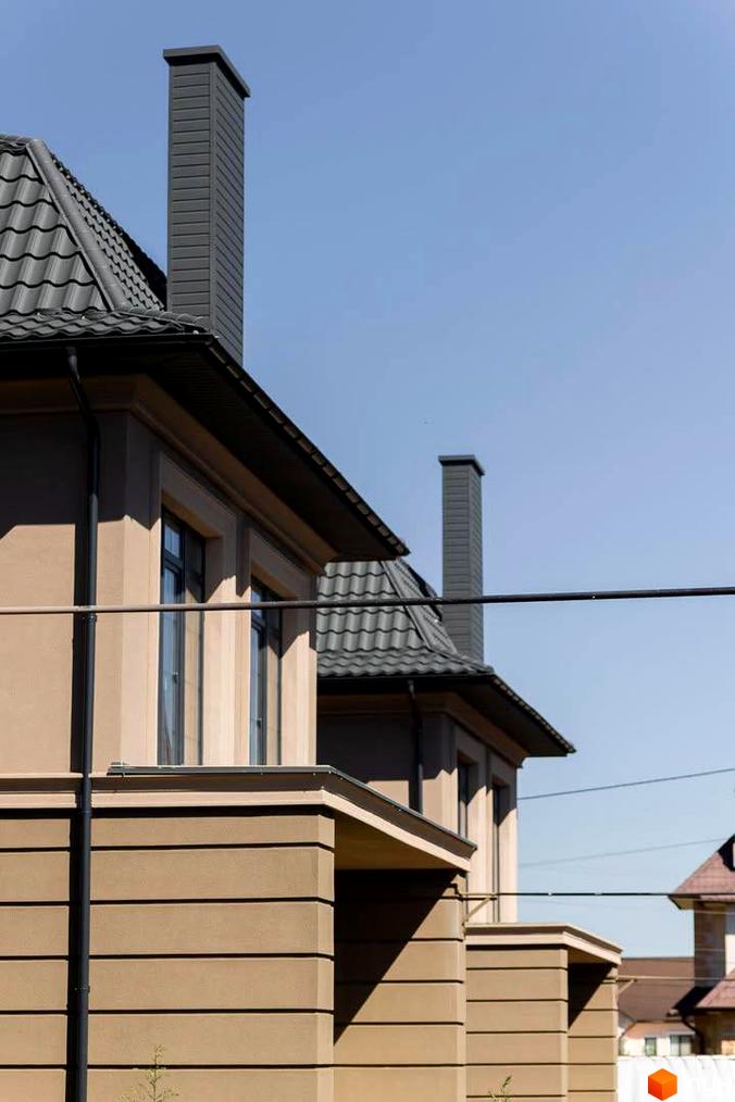 Зовнішній вигляд будинку в Котеджному містечку 5 element з сірим дахом та димарями. Фасад будинку бежевого кольору з горизонтальними лініями.