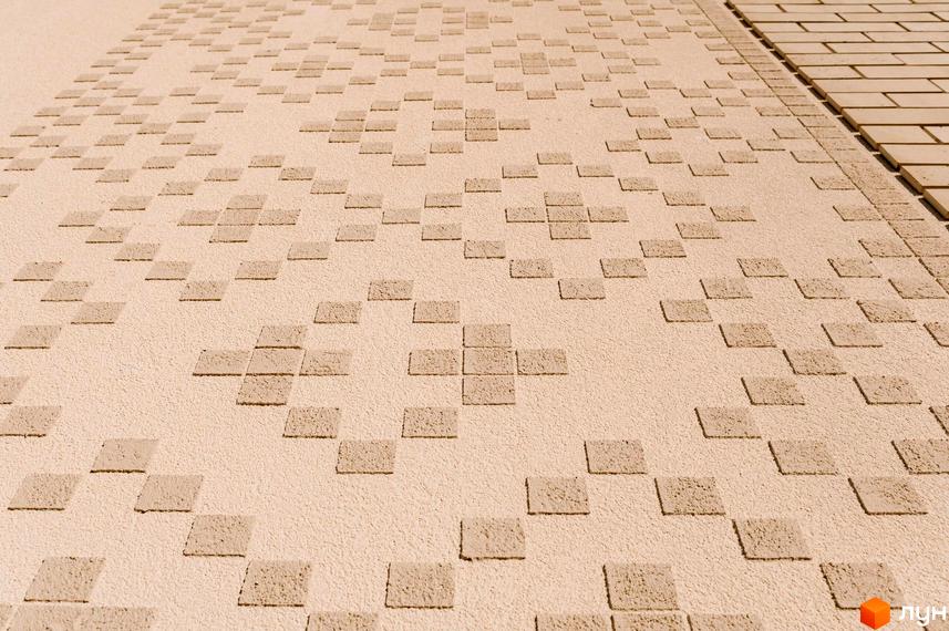 Фасад будинку у Котеджному містечку Етнія з оздобленням у вигляді квадратів. Вигляд стіни з оздоблювальними матеріалами.