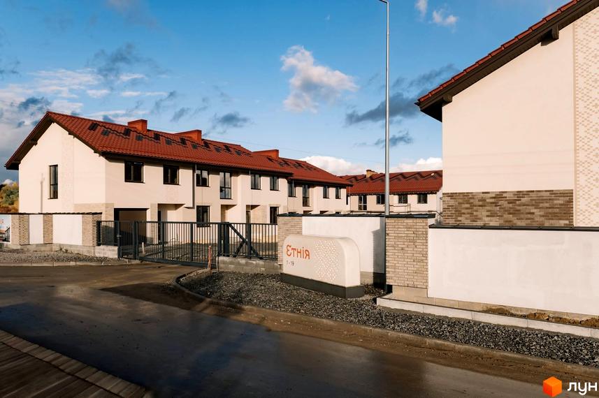 Зовнішній вигляд Котеджного містечка Етнія з будинками з червоними дахами. На передньому плані вхідна група та дорога.