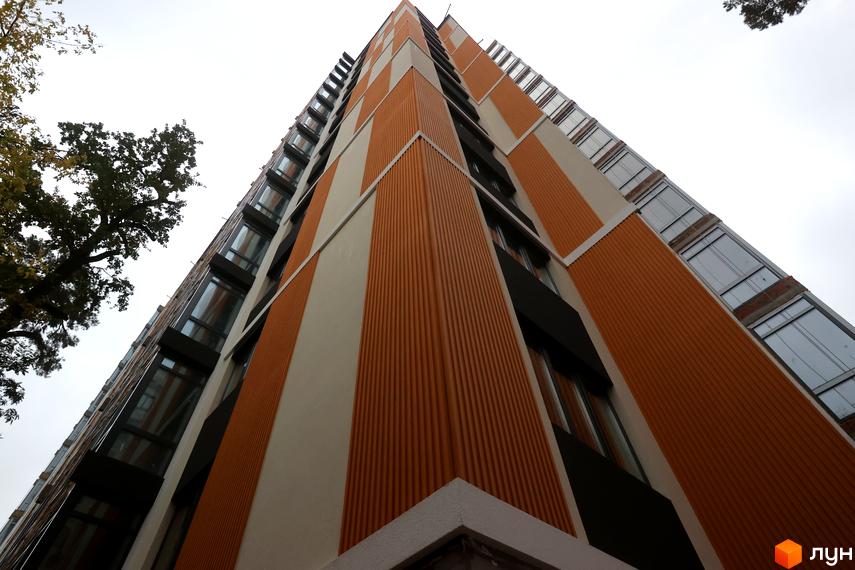 Зображення фасаду багатоповерхового будинку Житлового комплексу Фаворит Premium з великими вікнами та оздобленням під дерево.