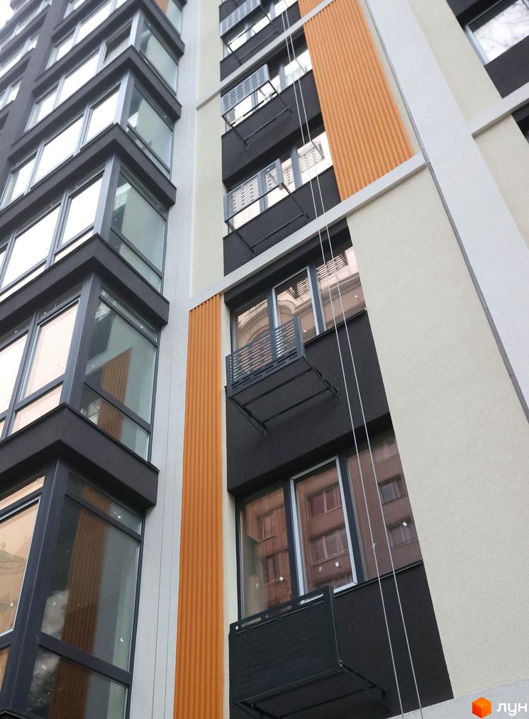 Зовнішній вигляд будинку в Житловому комплексі Фаворит Premium з великими вікнами та балконами. Фасад оздоблений в світлих та темних тонах.