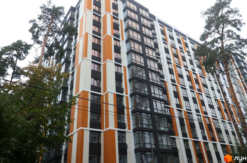 Зображення фасаду Житлового комплексу Фаворит Premium з великими вікнами та яскравим оздобленням. Навколо комплексу ростуть дерева.