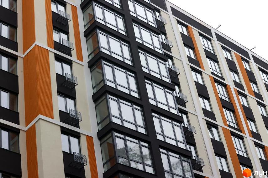 Зовнішній вигляд Житлового комплексу Фаворит Premium з великими вікнами та балконами. Фасад будинку пофарбований у різні кольори.