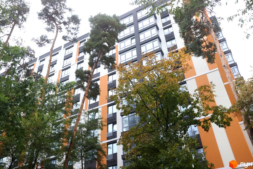 Зовнішній вигляд багатоповерхового будинку в Житловому районі Favorit Premium. Навколо будинку ростуть дерева.