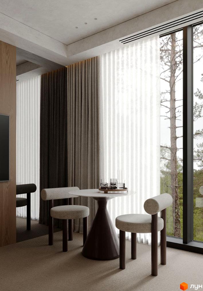 Інтер'єр кімнати з круглим столом та двома стільцями біля вікна з видом на дерева. Crystal Hills – ідеальне місце для життя в гармонії з природою.