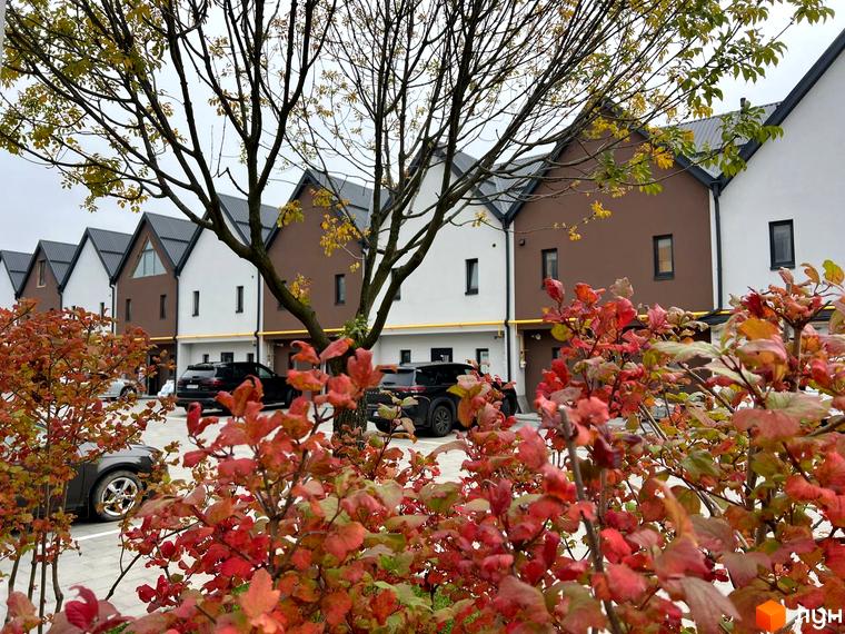 Зовнішній вигляд будинків у Житловому комплексі Sanville Park. На передньому плані кущі з червоним листям.