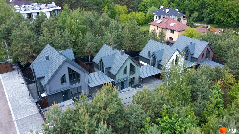 Вид зверху на котеджі з сірими дахами в Котеджному містечку Strilets'sky. Навколо будинків багато зелених дерев.