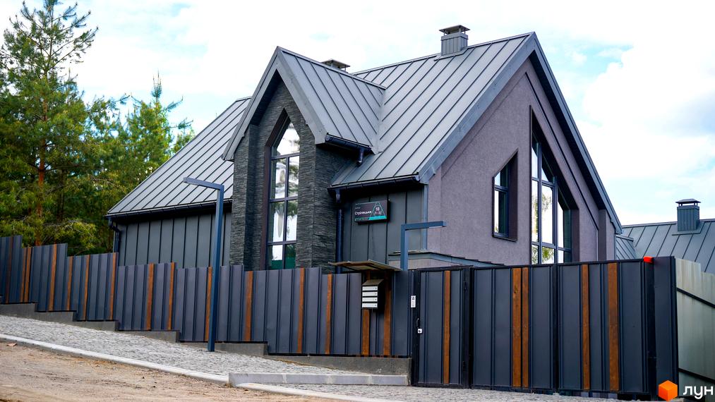 Зображення будинку в Котеджному містечку Strilets'sky з металевим дахом та великими вікнами. Навколо будинку встановлено металевий паркан.