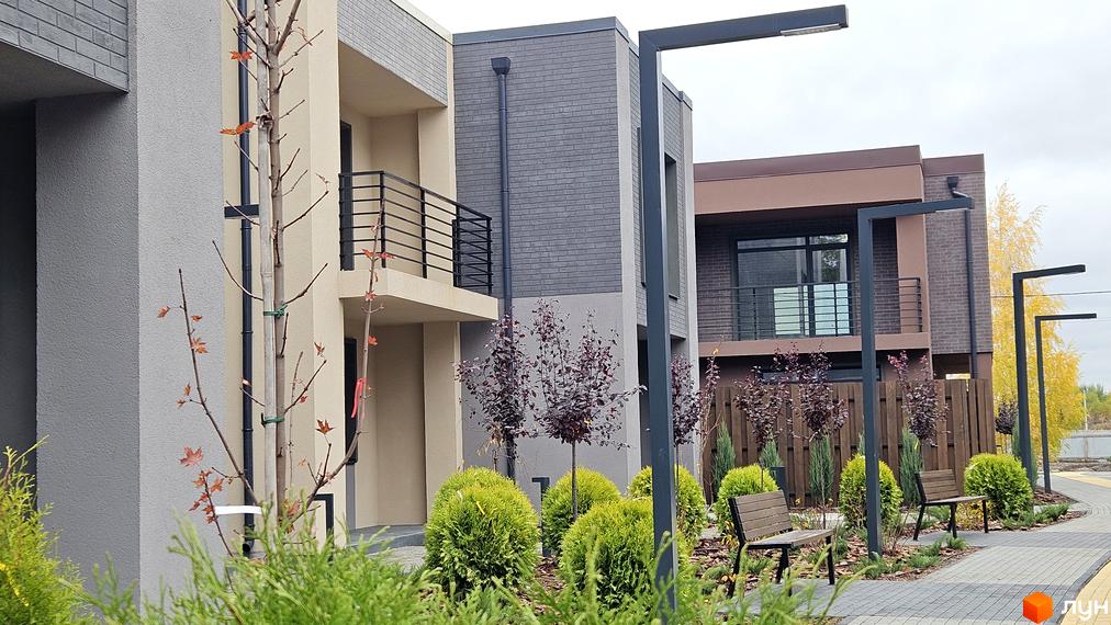 Зображення таунхаусів Sвій Dім 2. Вигляд фасаду будинку та озеленену прибудинкову територію з лавками.