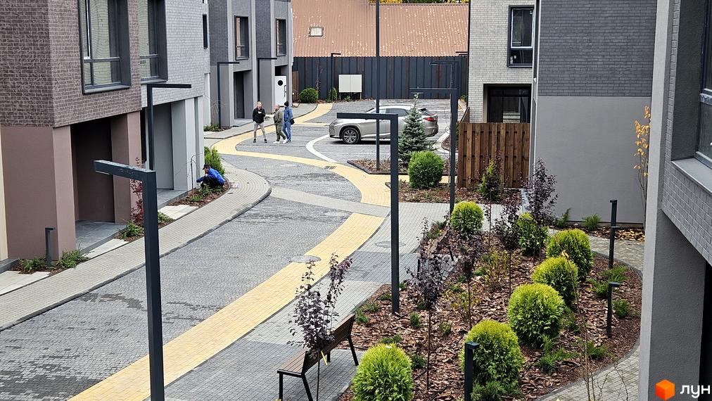 Вигляд на таунхауси Sвій Dім 2 з облаштованою прибудинковою територією. На подвір'ї ландшафтний дизайн, пішохідні доріжки та парковка.