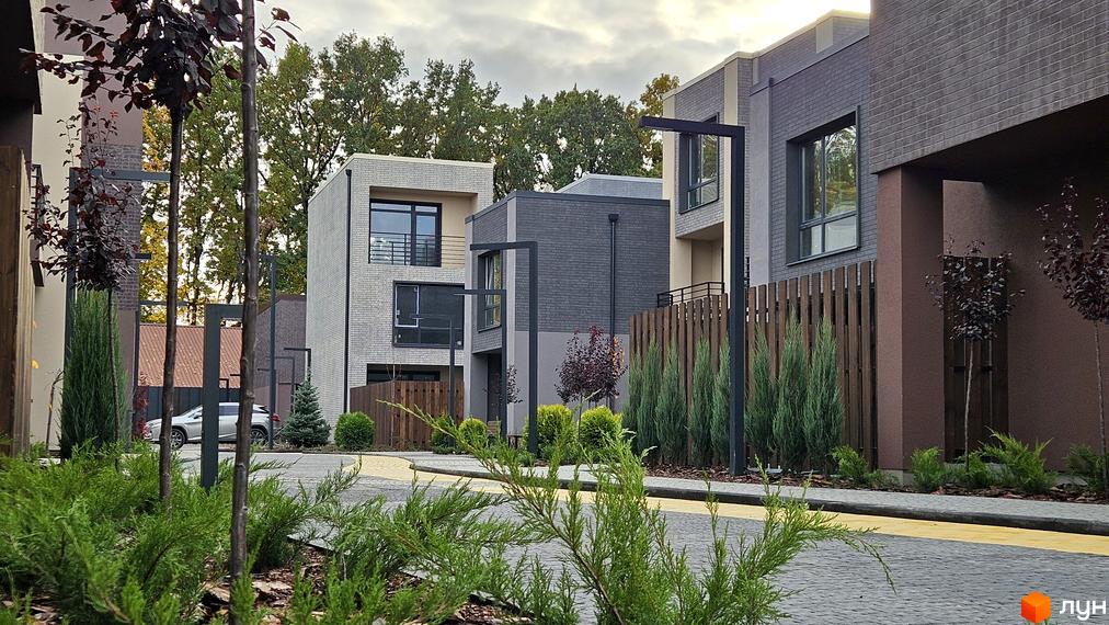 Зовнішній вигляд таунхаусів Sвій Dім 2 з сірого цегли. Навколо зелені насадження та акуратні доріжки.