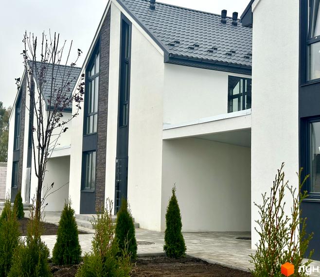 Зовнішній вигляд таунхаусів в Котеджному містечку DESNA HOMES. Фасад будинку з великими вікнами та акуратний двір з молодими туями.