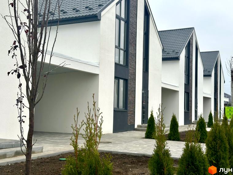 Зображення будинків в Котеджному містечку DESNA HOMES. Фасади білого кольору з темними вставками, сірі дахи, перед будинками висаджені туї.