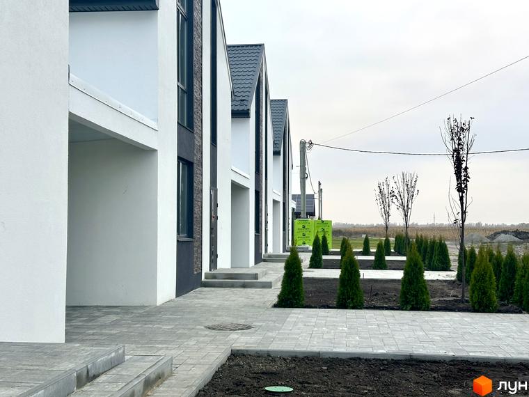 Вигляд будинків у Котеджному містечку DESNA HOMES. На передньому плані тротуарна плитка та зелені насадження.