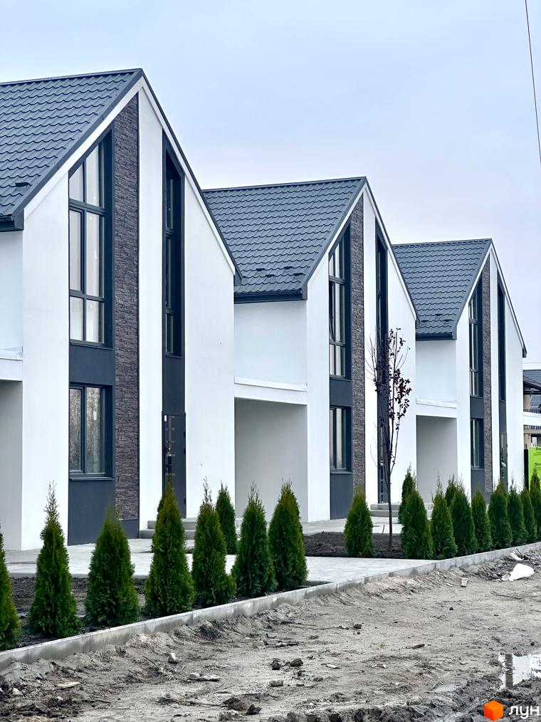 Зображення таунхаусів в Котеджному містечку DESNA HOMES. Двоповерхові будинки з сірими дахами та білими стінами, перед будинками висаджені туї.