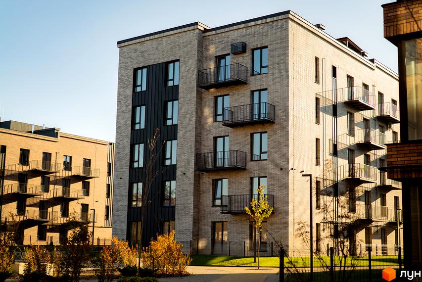 Зовнішній вигляд будинку в Житловому комплексі Долішній. Багатоповерхова будівля з балконами та великими вікнами.
