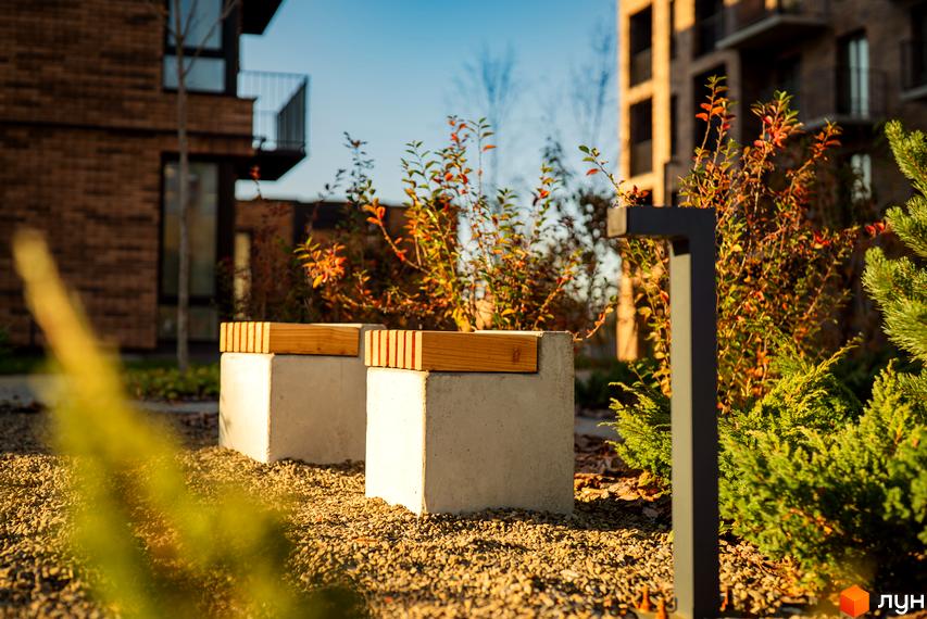 Зображення території Житлового комплексу Долішній з лавками та освітленням. На задньому плані видно фасади будинків.