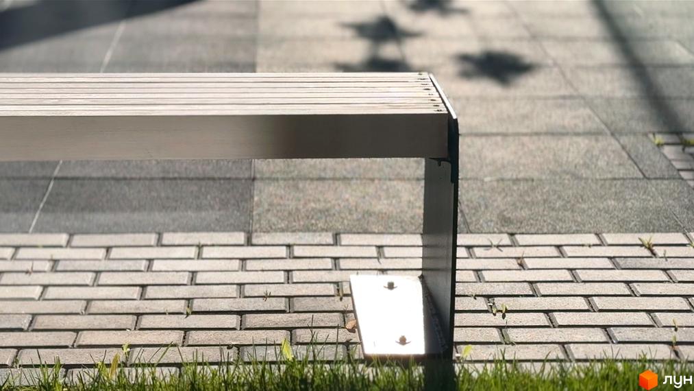 Фото лавки біля тротуару з плитки. Будівельний проєкт Стандарт має зручні місця для відпочинку на території.