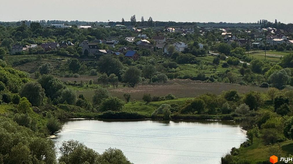 Панорамний вид на Житловий комплекс Стандарт з будинками та озелененою територією. Видно дахи будинків серед зелені.