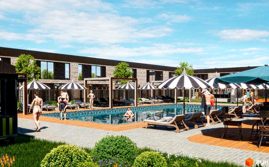 Вигляд на басейн з людьми в комплексі Hollywood. На задньому плані малоповерхова забудова з цегли та дерева.