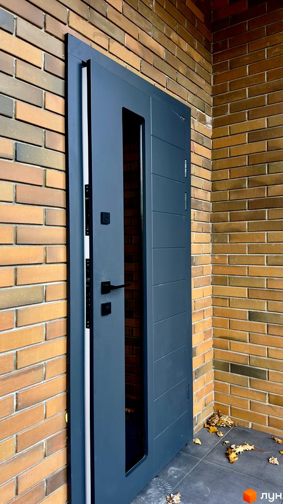 Відкриті вхідні двері в будинок в Житловому районі PARK PLACE. Цегляна кладка стін та плитка на підлозі.