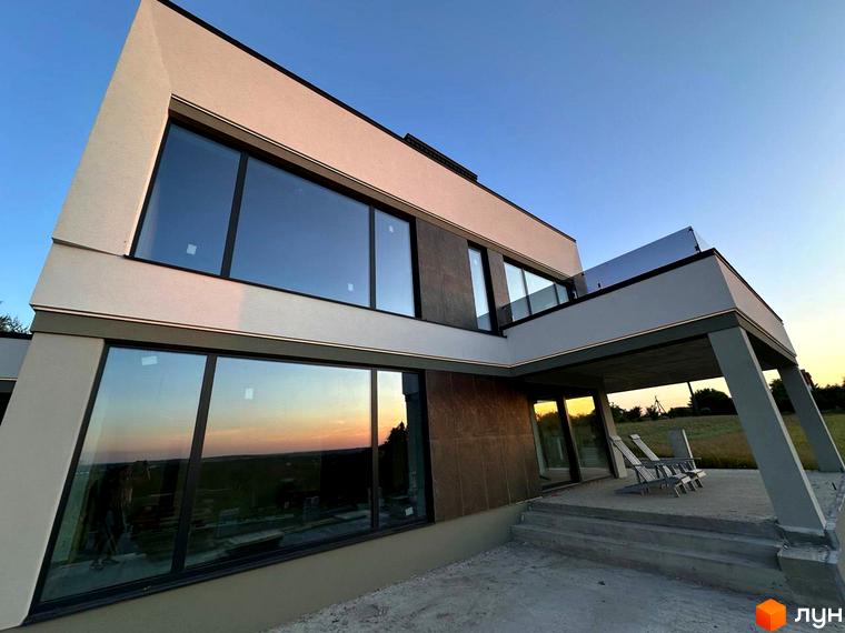 Двоповерховий будинок з великими вікнами та терасою. На території Котеджне містечко Belvedere є місце для відпочинку.