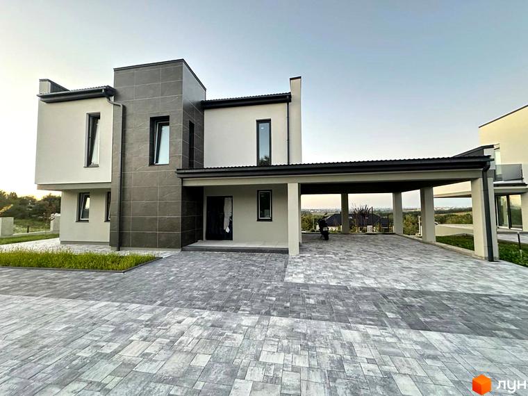 Зображення будинку в Містечко котеджів Belvedere з сірим фасадом та просторою прибудинковою територією з бруківкою.