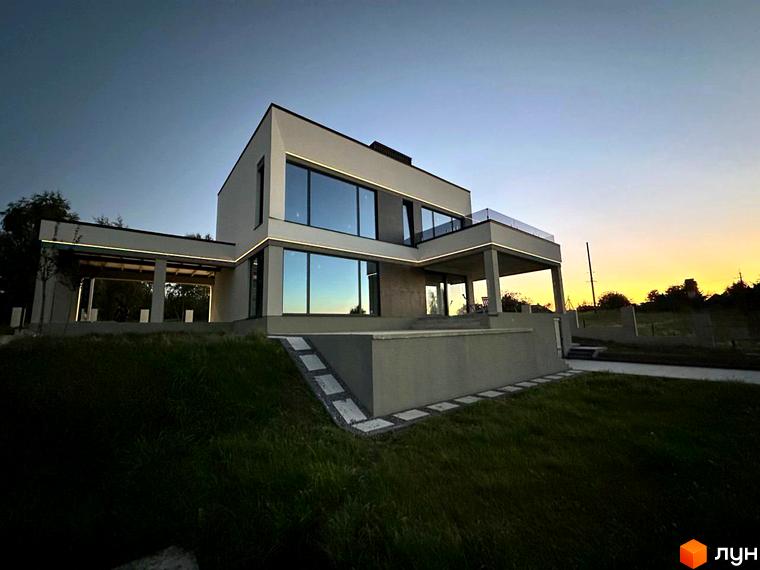 Двоповерховий будинок з великими вікнами та терасою в Котеджному містечку Belvedere. На передньому плані газон та доріжка з плитки.