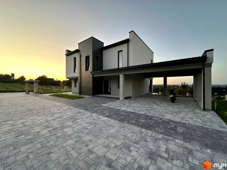 Фасад будинку КМ Belvedere з великими вікнами та навісом для авто. Бруківка на прибудинковій території.