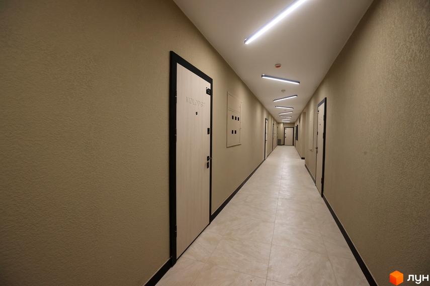 Коридор в новобудові ЖК Атмосфера з дверима та світлодіодним освітленням. Стіни оздоблені декоративною штукатуркою, підлога з плиткою.